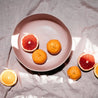 Handmade Dusty Pink Fruit bowl by Palinopsia Ceramics on a linen sheet with bright citrus in Sydney Australia 
