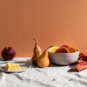 Sunny table top with Palinopsia handmade ceramics styled with pure linen napery and fruit in a still life inspired shot. 