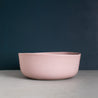 Handmade fruit bowl in dusty pink with organic shape against a navy blue wall by Palinopsia Ceramics in Sydney 
