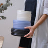 Sideview of a woman holding a stack of handmade dinner sets including dinner plates and bowls by Palinopsia Ceramics Australia 